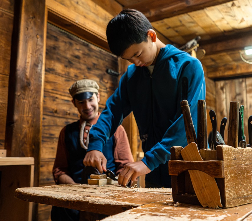 a young visitor to The Village at Black Creek receives a hands-on lesson heritage trades under the guidance of a costumed educator