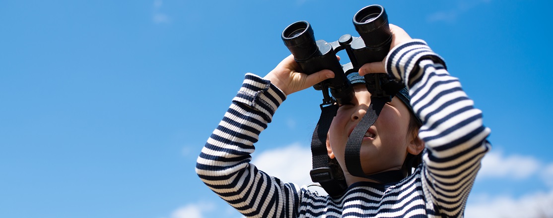 young boy looks through binoculars while participating in TRCA outdoor family summer fun experience