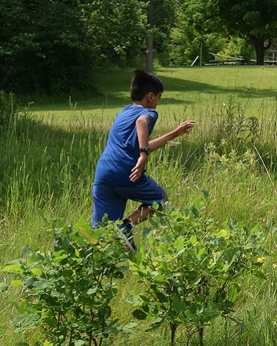 TRCA summer camper runs through field at Swan Lake Outdoor Education Centre