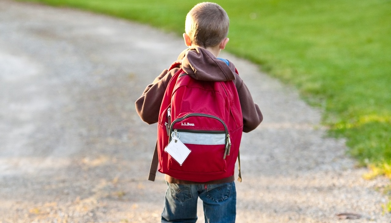 child with backpack walks to school