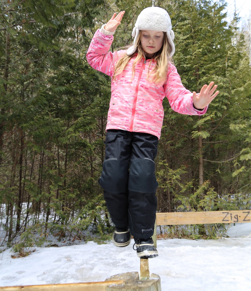 student walks on outdoor balance beam during winter mini camp at Claremont Nature Centre