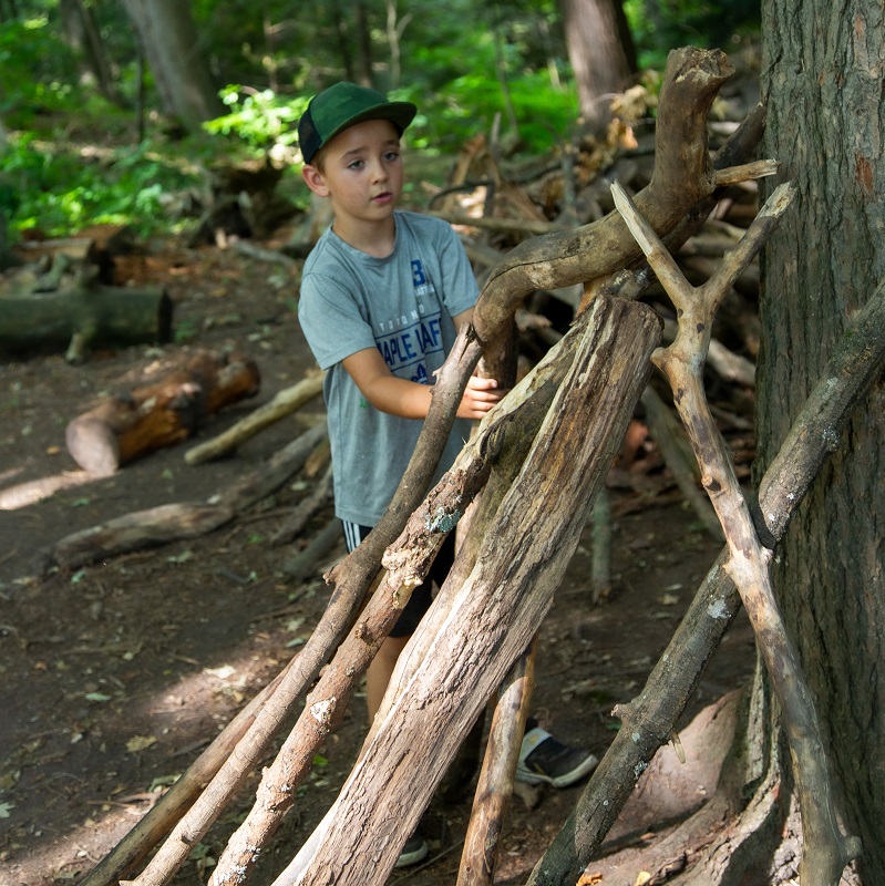 camper learns how to build a forest shelter at Claremont Nature Centre