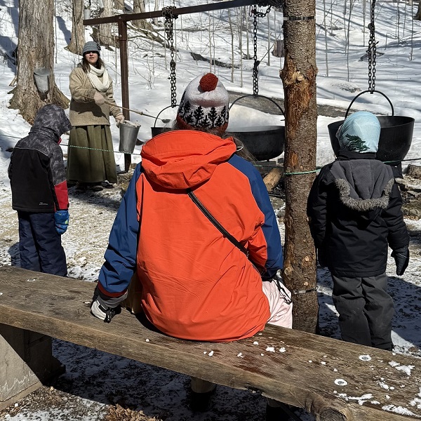 a family at Kortright Centre for Conservation enjoys a demonstration of the traditional method of making maple syrup