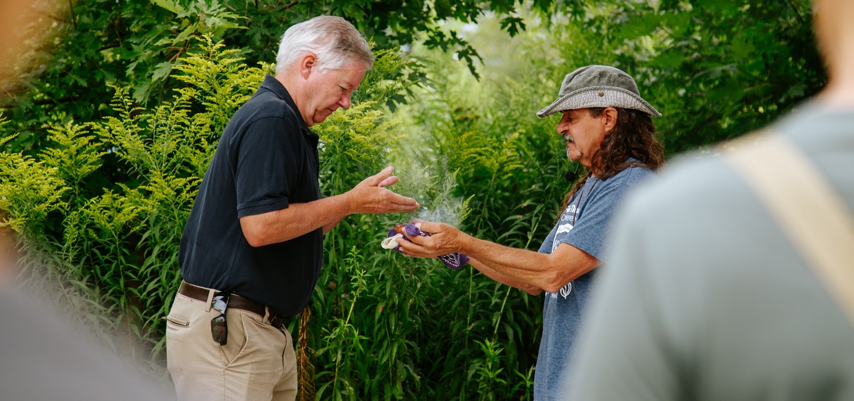 TRCA Board Chair Paul Ainslie smudging with Cat Criger as part of the opening of the 2024 TRCA Butterfly Festival at Tommy Thompson Park