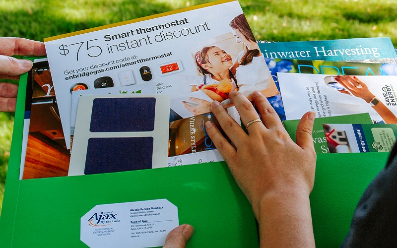 a SNAP team member and a neighbourhood resident leaf through a folder of Climate Ready Homes program resources
