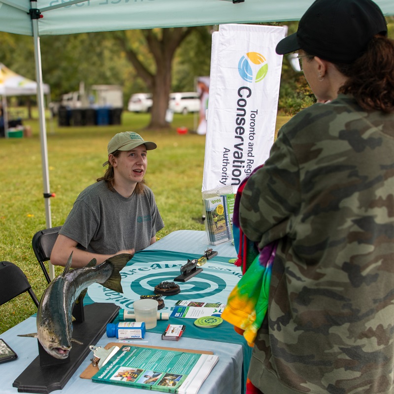 TRCA team member greets visitors at one of the many interactive stations at the Adventures of Salmon event at Morningside Park