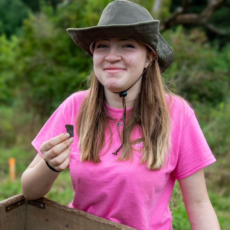 a student displays an artifact unearthed at the Boyd Archaeological Field School