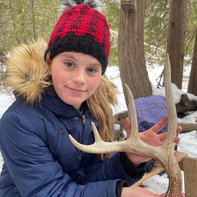a student on a overnight winter field trip examines a deer antler