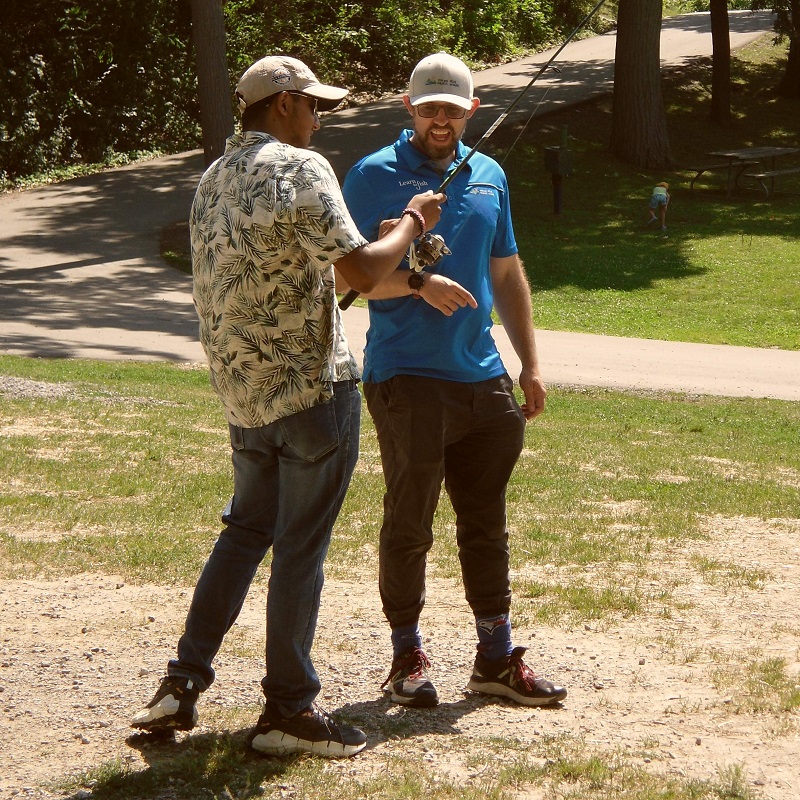 an experienced angler teaches a young man to use a fishing rod