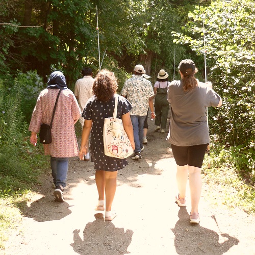 a group of anglers carrying fishing tackle walk along a trail toward the fishing area at Heart Lake Conservation Park