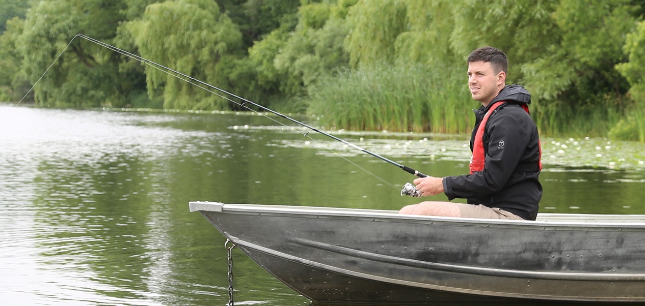 an angler fishes from a small boat on Heart Lake