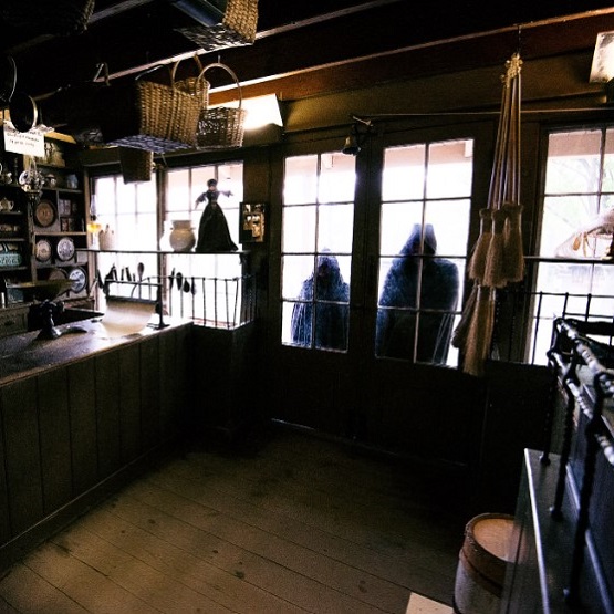 shadowy cloaked figures peer through the windows of a heritage building at The Village at Black Creek