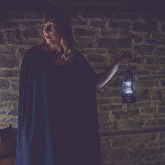 a cloaked guide leads a haunted walk in one of the historic buildings of the Village at Black Creek