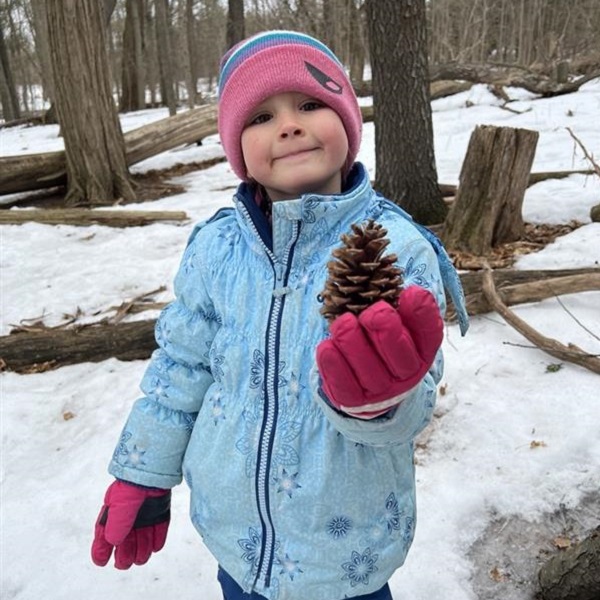 a student holds up a pine cone at a March Break camp at Lake St George Field Centre