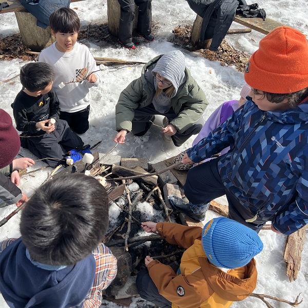 students toast marshmallows over a campfire at a March Break camp at Lake St George Field Centre