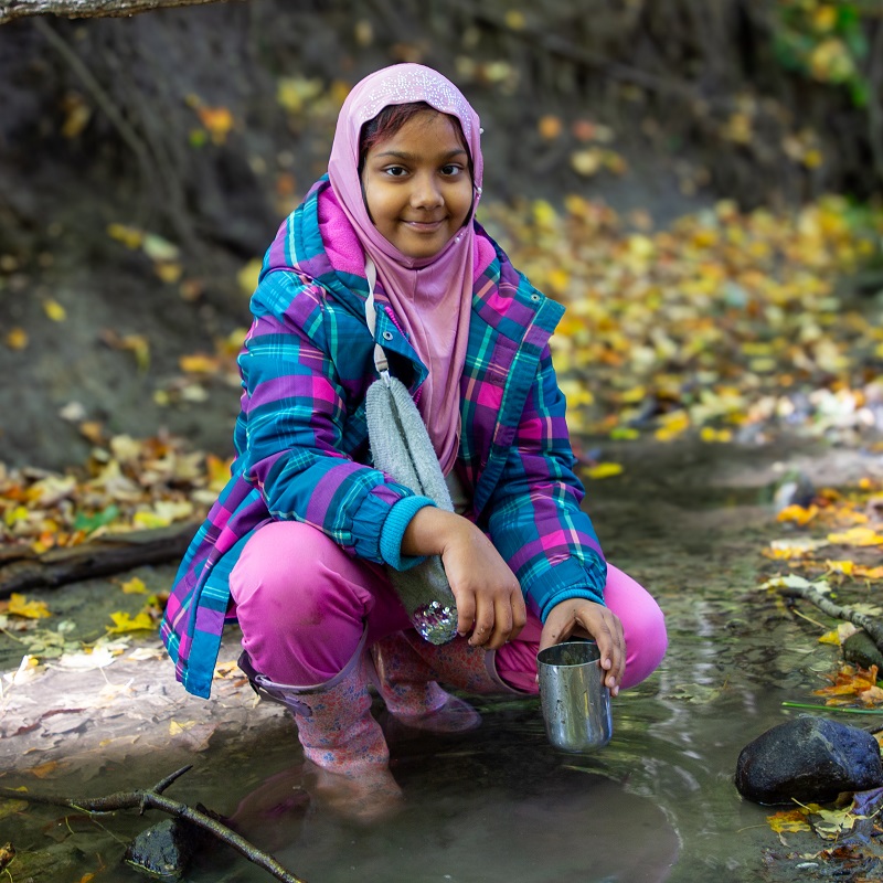 a student at The Nature School at Claremont Nature Centre explores a stream bed