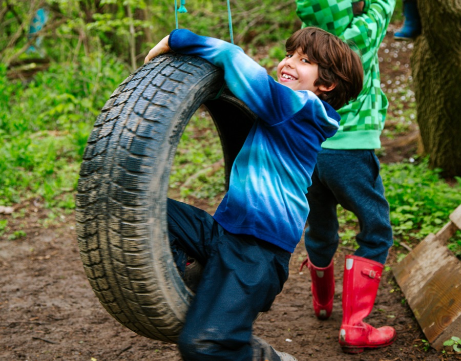 a student plays on a tire swing at The Nature School at Claireville Conservation Area