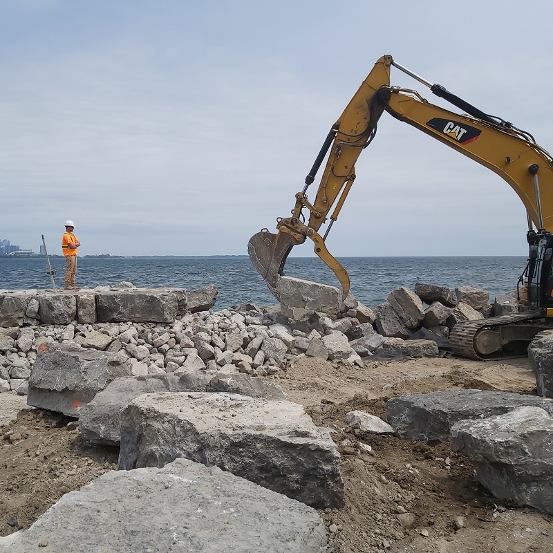 a TRCA team member oversees the use of heavy machinery on a Lake Ontario Shoreline erosion protection project