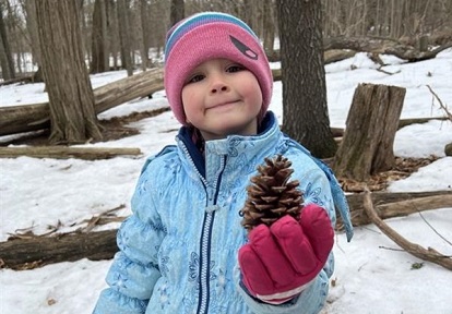 a student holds up a pine cone at a March Break camp at Lake St George Field Centre