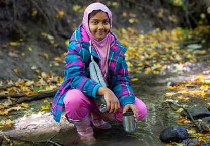 a student in The Nature School at Claireville in Brampton explores a stream bed
