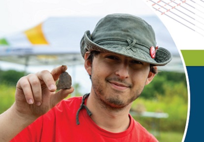 a high school student holds up an artifact discovered at the Boyd Archaeological Field School