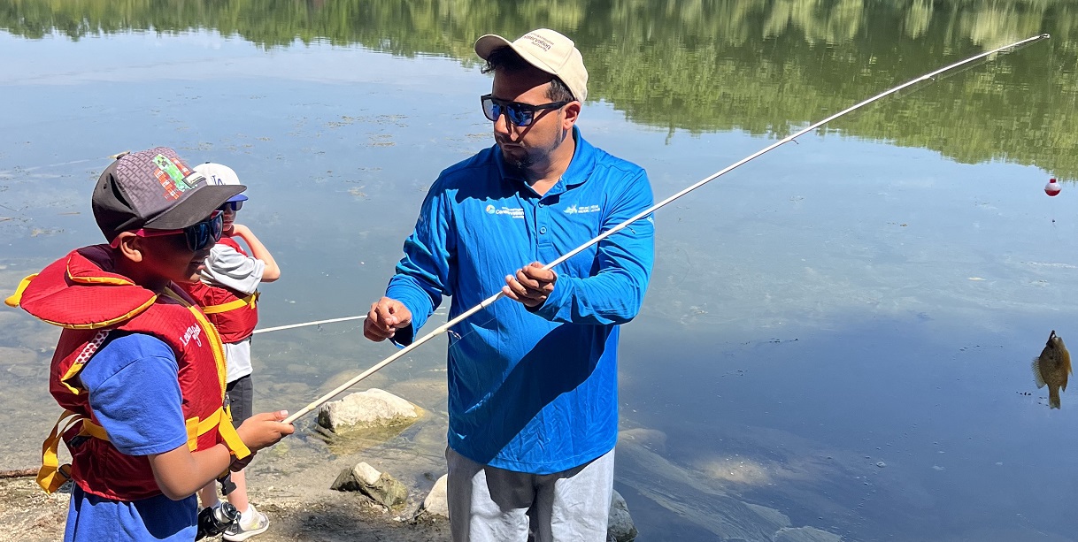 an instructor in the Learn to Fish program at Heart Lake Conservation Park teaches a youngster the basics of angling