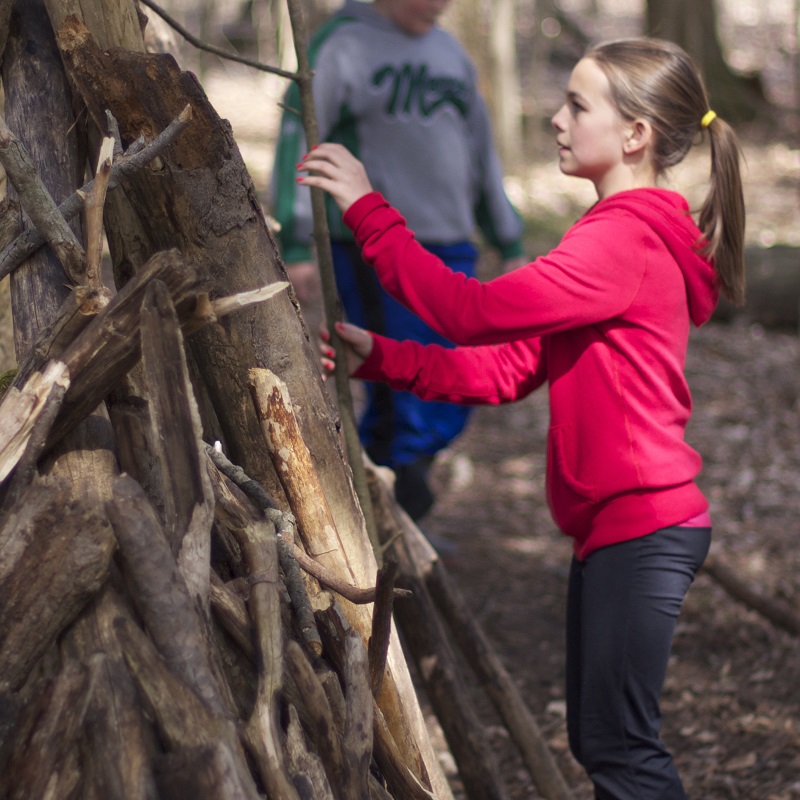 a student taking part in a community group program builds a shelter at Claireville Conservation Area in Brampton