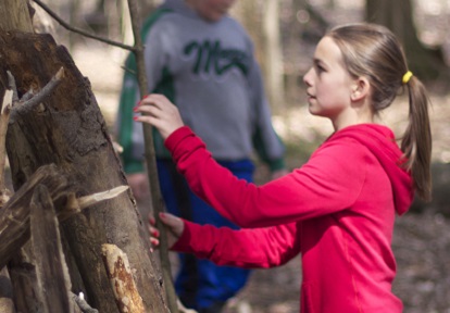 a student taking part in a community group program builds a shelter at Claireville Conservation Area in Brampton