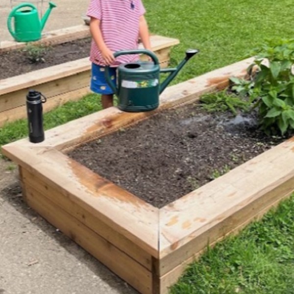 student tends to a new garden on school grounds