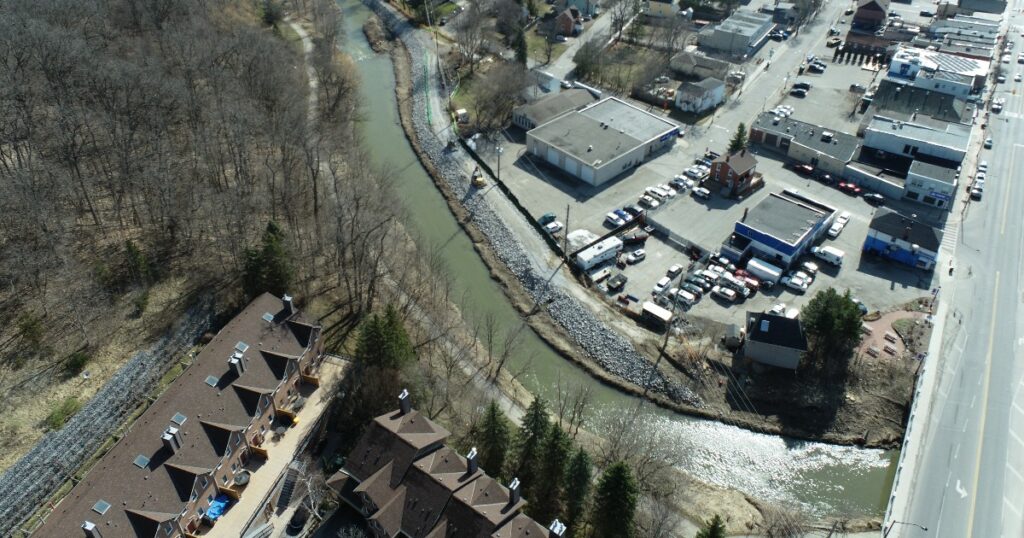 an aerial view of a river winding through a mixed commercial and residential area on a spring day