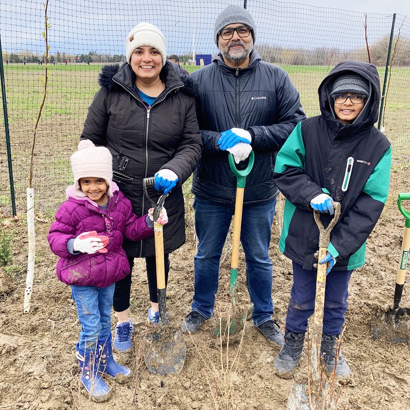 a family takes part in an Earth Week community planting event