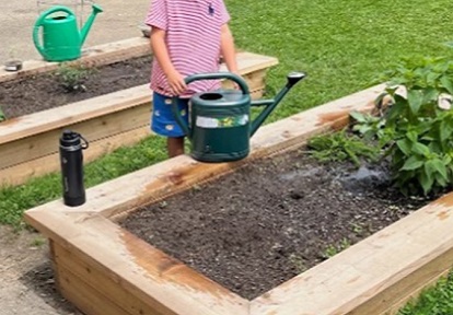 student tends to a new garden on school grounds